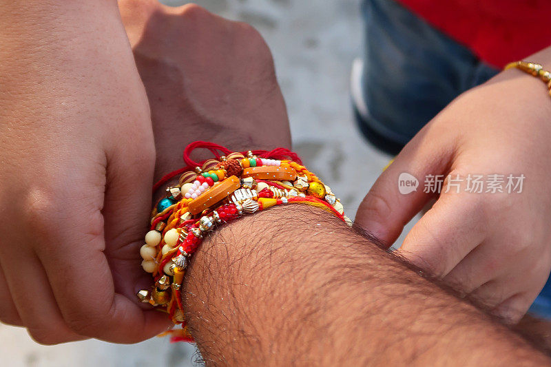 难以辨认的特写图像，印度，印度女孩系rakhi(串线手镯)在她哥哥的手腕上，Raksha Bandhan印度教的兄弟情谊和爱的节日，重点在前景